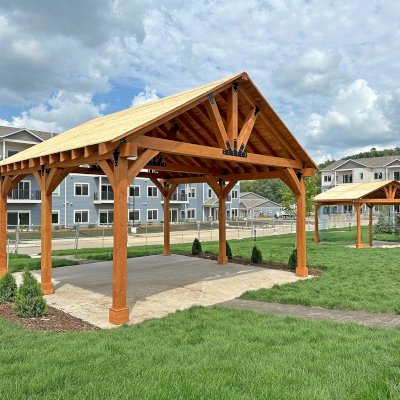Thick Timber Toledo Wood Pavilion (Options: 24' L x 24' W, Douglas-fir, 6-Post Anchor Kit for High-Wind, 10' H Posts, No Electrical Wiring Trim, 8 x 8 Posts and Top Chord of Trusses, 8 x 10 Supports and Bottom Chord of Trusses, 2 x 8 Rafters, No Fan Bases, Transparent Premium Sealant). Final Roofing Skin Pending Installation. Photo Also Shows a Del Norte Pavilion. Photo Courtesy of S. Fenske of Rochester, Minnesota.