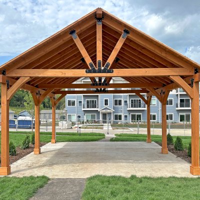 Thick Timber Toledo Wood Pavilion (Options: 24' L x 24' W, Douglas-fir, 6-Post Anchor Kit for High-Wind, 10' H Posts, No Electrical Wiring Trim, 8 x 8 Posts and Top Chord of Trusses, 8 x 10 Supports and Bottom Chord of Trusses, 2 x 8 Rafters, No Fan Bases, Transparent Premium Sealant). Final Roofing Skin Pending Installation. Photo Courtesy of S. Fenske of Rochester, Minnesota.