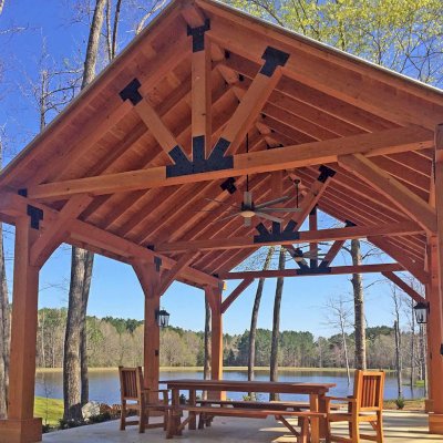 Thick Timber Toledo Wood Pavilions (Options: 26' L x 20' W, Douglas-fir, 6-Post Anchor Kit for High-Wind, Electrical Wiring Trim for 3 Posts, 10 x 10 Supports and Posts, 8 x 8 Rafters, Transparent Premium Sealant). Photo Also Shows a Patio Table Set with Side Benches and End Chairs. Photo Courtesy of M. Turner of Thaxton, MS.