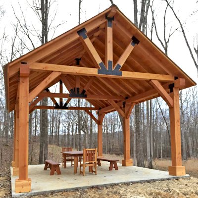 Thick Timber Toledo Wood Pavilion (Options: 26' L x 20' W, Douglas-fir, 6-Post Anchor Kit for High-Wind, Electrical Wiring Trim for 3 Posts, 10 x 10 Supports and Posts, 8 x 8 Rafters, Transparent Premium Sealant). Photo Also Shows a Patio Table Set with Side Benches and End Chairs. Photo Courtesy of M. Turner of Thaxton, MS.