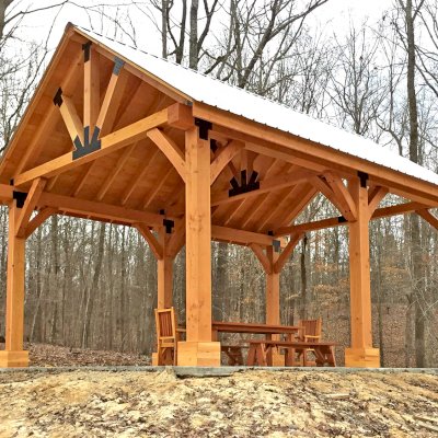 Thick Timber Toledo Wood Pavilion (Options: 26' L x 20' W, Douglas-fir, 6-Post Anchor Kit for High-Wind, Electrical Wiring Trim for 3 Posts, 10 x 10 Supports and Posts, 8 x 8 Rafters, Transparent Premium Sealant). Photo Also Shows a Patio Table Set with Side Benches and End Chairs. Photo Courtesy of M. Turner of Thaxton, MS.