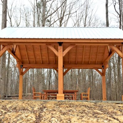 Thick Timber Toledo Wood Pavilion (Options: 26' L x 20' W, Douglas-fir, 6-Post Anchor Kit for High-Wind, Electrical Wiring Trim for 3 Posts, 10 x 10 Supports and Posts, 8 x 8 Rafters, Transparent Premium Sealant). Photo Also Shows a Patio Table Set with Side Benches and End Chairs. Photo Courtesy of M. Turner of Thaxton, MS.