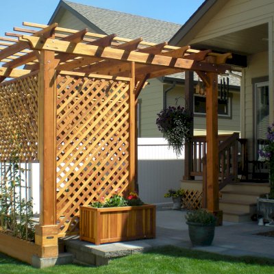 Traditional Wooden Garden Pergola (Options: 10' L x 12' W, California Redwood, No Electrical Wiring Trim, Open Roof with Slats at 18", Rafters at 18", Widthwise Roof Support Timbers, 4-Post Anchor Kit for Stone, No Ceiling Fan Base, 3 Privacy Panels, No Curtain Rods, 9' Post Height, Transparent Premium Sealant). Photo Courtesy of Bill and Sandy Gibson of Coeur d'Alene, Idaho.