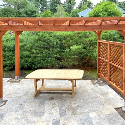 Traditional Wooden Garden Pergola (Options: 16' L x 10' W, California Redwood, 1 Electrical Wiring Trim, Open Roof with Slats at 18", Rafters at 18", 4-Post Anchor Kit for Concrete, No Ceiling Fan Base, 2 Lattice Privacy Panels, No Curtain Rods, 9' Posts [Posts Were Placed Slightly Off Parallel Due to Spatial Constraints], Transparent Premium Sealant). Photo Courtesy of D. DelVecchio of North Grafton, Massachusetts.