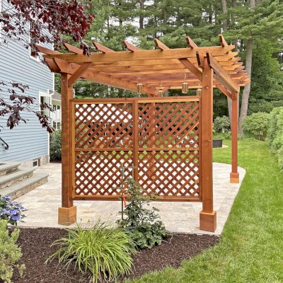 Traditional Wooden Garden Pergola (Options: 16' L x 10' W, California Redwood, 1 Electrical Wiring Trim, Open Roof Rafters at 18" [Top Slats Replaced by a Second Layer of Rafters by Custom Request], 4-Post Anchor Kit for Concrete, No Ceiling Fan Base, 2 Lattice Privacy Panels, No Curtain Rods, 9' Posts [Posts Were Placed Slightly Off Parallel Due to Spatial Constraints], Transparent Premium Sealant). Photo Courtesy of D. DelVecchio of North Grafton, Massachusetts.