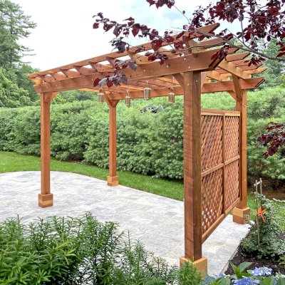Traditional Wooden Garden Pergola (Options: 16' L x 10' W, California Redwood, 1 Electrical Wiring Trim, Open Roof Rafters at 18" [Top Slats Replaced by a Second Layer of Rafters by Custom Request], 4-Post Anchor Kit for Concrete, No Ceiling Fan Base, 2 Lattice Privacy Panels, No Curtain Rods, 9' Posts [Posts Were Placed Slightly Off Parallel Due to Spatial Constraints], Transparent Premium Sealant). Photo Courtesy of D. DelVecchio of North Grafton, Massachusetts.