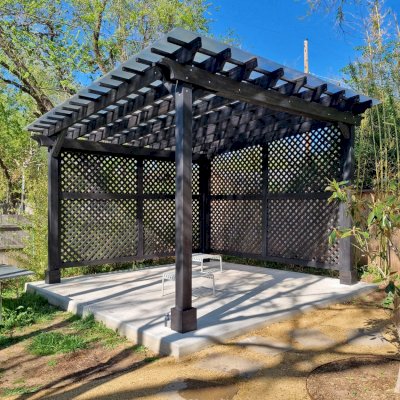 Traditional Wooden Garden Pergola (Options: 15' L x 15' W, Mosaic Redwood, No Electrical Wiring Trim, Open Roof with Slats at 12", Rafters at 18", with Rain Guard,  4-Post Anchor Kit for Concrete, No Ceiling Fan Base, 2 Full Wall Lattice Privacy Panels, No Curtain Rods, 9.5' Posts, Black Stain Premium Sealant). Photo Courtesy of J. McCalmont of Oklahoma City, OK.