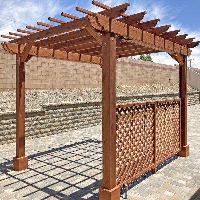 Traditional Wooden Garden Pergola (Options: 10' L x 12' W, Mature Redwood, Electrical Wiring Trim Kit for 2 Posts, Open Roof with Slats at 12", Rafters at 18", No Rain Guard,  4-Post Anchor Kit for High-Wind, No Ceiling Fan Base, 1 Lattice Privacy Panel, No Curtain Rods, Corbel End Cut Detail, 9' Posts, Transparent Premium Sealant). Photo Courtesy of J. Downing of Beaumont, CA.