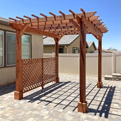 Traditional Wooden Garden Pergola (Options: 10' L x 12' W, Mature Redwood, Electrical Wiring Trim Kit for 2 Posts, Open Roof with Slats at 12", Rafters at 18", No Rain Guard,  4-Post Anchor Kit for High-Wind, No Ceiling Fan Base, 1 Lattice Privacy Panel, No Curtain Rods, Corbel End Cut Detail, 9' Posts, Transparent Premium Sealant). Photo Courtesy of J. Downing of Beaumont, CA.
