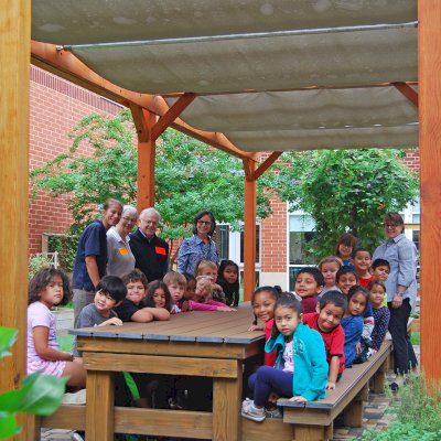 Traditional Wooden Garden Pergola (Options: 30' L x 12' W, Douglas-fir, Open Roof with Slats at 18, Transparent Premium Sealant). Shade clothe is a wonderful way to increase shade when needed. Shade Clothe shown is a custom detail we can add for you. Photo Courtesy of Frederick Douglass Elementary School of Lessburg, Virginia.