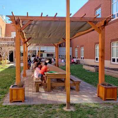 Traditional Wooden Garden Pergola (Options: 30' L x 12' W, Douglas-fir, Open Roof with Slats at 18, Transparent Premium Sealant). Shade clothe is a wonderful way to increase shade when needed. Shade Clothe shown is a custom detail we can add for you. Photo Courtesy of Frederick Douglass Elementary School of Lessburg, Virginia.