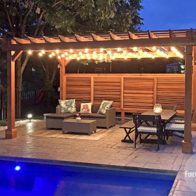 Traditional Wooden Garden Pergola (Options: 18' L x 12' W, California Redwood, 1 Electrical Wiring Trim, Open Roof with Slats at 12", Rafters at 18", Lengthwise Roof Support Timbers, 4-Post Anchor Kit for Concrete, No Ceiling Fan Base, 1 Louver Privacy Panel Half Height Without Wall, 1 Curtain Rods, 9' Post Height, Transparent Premium Sealant). Photo Courtesy of Sasha Antskaitis of Louisville, Kentucky.