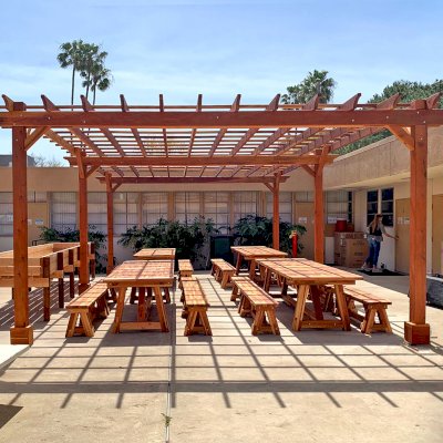 Traditional Wooden Garden Pergola (Options: 30' L x 18' W, California Redwood, Electrical Wiring Trim for 2 Posts, Open Roof with Slats at 18", Rafters at 18", 6-Post Anchor Kit for Concrete, No Ceiling Fan Base, No Privacy Panels, No Curtain Rods, 10' Post Height, Transparent Premium Sealant). Photo also shows 4 Classic Redwood Patio Tables. Photo Courtesy of T. Sirvent of Costa Mesa, CA.