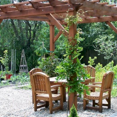 Traditional Wooden Garden Pergola (Options: 12' L x 12' W, Old-Growth Redwood, No Electrical Wiring Trim, Open Roof with Slats at 18", Rafters at 18", 4 Post Anchor Kit for Stone, No Ceiling Fan Base, No Privacy Panels, No Curtain Rods, 9' Post Height, Transparent Premium Sealant). 4 ft Square Patio Table Set with Luna Armchairs Under the Pergola. Photo Courtesy of Ms. Anne Eccles of Lexington, MA.