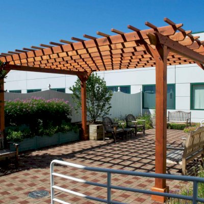 Traditional Wooden Garden Pergola (Options: 18' L x 14' W, California Redwood, No Electrical Wiring Trim, Open Roof with Slats at 12", Rafters at 18", Widthwise Roof Support Timbers, 4-Post Anchor Kit For Stone, No Ceiling Fan Base, No Privacy Panels, No Curtain Rods, 9' Post Height, Transparent Premium Sealant). Photo Courtesy of Dartmouth Hitchcock Medical Center, Lebanon.