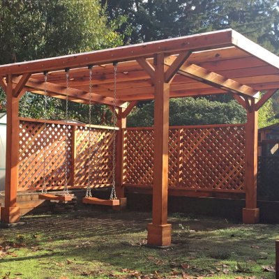Custom Traditional Wooden Garden Pergola (Options: 18' x 15', California Redwood, No Electrical Wiring Trim, Widthwise Roof Supports TImbers, 4-Post Anchor Kit for Stone, 2 Privacy Panels, No Curtain Rods, Roof with a Slope, Transparent Sealant) with 2 Rory's Swing Seats, Added by Custom Request. Customer Added Lexan Panels. Photo Courtesy of Tina Phi of Palo Alto, CA.