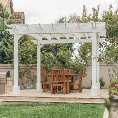 Traditional Wooden Garden Pergola (Options: 13' L x 12' W, Douglas-fir, 1 Electrical Wiring Trim, Open Roof with Slats at 6", Rafters at 18", 4-Post Anchor Kit for Concrete, No Ceiling Fan Base, No Privacy Panels, 1 Electrical Wiring Trim Kit, 9' Posts, Off-White Oil-Based Primer). Photo Also Shows a San Francisco Patio Table with Chairs in Mature Redwood. Photo Courtesy of J. Schulte of Laguna Niguel, CA.