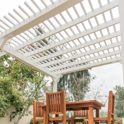 Traditional Wooden Garden Pergola (Options: 13' L x 12' W, Douglas-fir, 1 Electrical Wiring Trim, Open Roof with Slats at 6", Rafters at 18", 4-Post Anchor Kit for Concrete, No Ceiling Fan Base, No Privacy Panels, 1 Electrical Wiring Trim Kit, 9' Posts, Off-White Oil-Based Primer). Photo Also Shows a San Francisco Patio Table with Chairs in Mature Redwood. Photo Courtesy of J. Schulte of Laguna Niguel, CA.