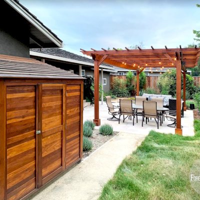 Traditional Wooden Garden Pergola (Options: 25' L x 14' W, California Redwood, Electrical Wiring Trim for 2 Posts, Open Roof with Slats at 18", with 2' Overhang by Custom Request, Rafters at 12", 4-Post Anchor Kit for High-Wind, No Ceiling Fan Base, No Privacy Panels, Curtain Rods on 2 Sides, 9.5' Post Height, Transparent Premium Sealant). Photo Also Shows a Storage Shed. Photo Courtesy of J. Lewis of Mountain View, CA.
