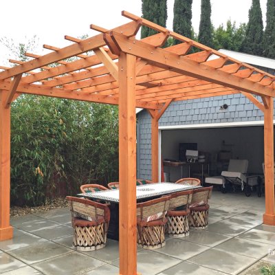 Traditional Wooden Garden Pergola (Options: 15' L x 12' W, Douglas-fir, Electrical Wiring Trim for 1 Post, Open Roof with Slats at 18", Rafters at 18", Lengthwise Roof Support Timbers, 6-Post Anchor Kit for Concrete, 1 Ceiling Fan Base, No Privacy Panels, No Curtain Rods, Custom 45 Degree End Cuts for Rafters and Support Timbers, 9' Post Height, Transparent Premium Sealant). Photo Courtesy of L. Martling of Los Angeles, CA.