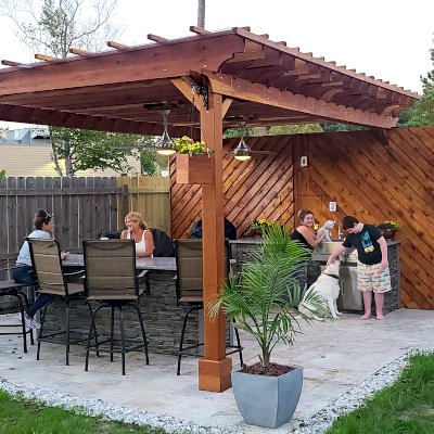 Traditional Wooden Garden Pergola (Options: 18' L x 12' W, California Redwood, 1 Electrical Wiring Trim, Open Roof with Slats at 18", Rafters at 12" by Custom Request, with Rain Guard, 4-Post Anchor Kit for High-Wind, 2 Ceiling Fan Bases, No Privacy Panels, No Curtain Rods, 9.5' Posts, Transparent Premium Sealant). Rafters were designed with a slope for draining purpose. Photo Courtesy of M. McGourty of Virginia Beach, Virginia.
