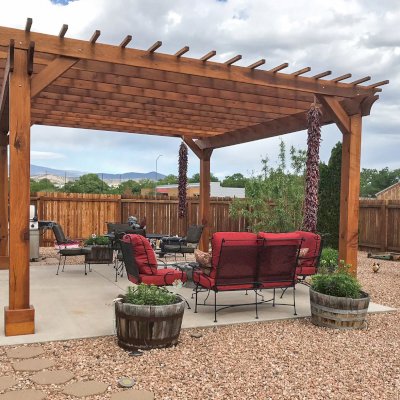 Traditional Wooden Garden Pergola (Options: 16' L x 20' W, California Redwood, No Electrical Wiring Trim, Open Roof with Slats at 12", Rafters at 18", 4-Post Anchor Kit for Concrete, No Ceiling Fan Base, No Privacy Panels, 1 Curtain Rods, 9' Posts, Transparent Premium Sealant). Thicker Timbers by Custom Request. Photo Courtesy of P. Rauenzahn of Espanola, New Mexico.