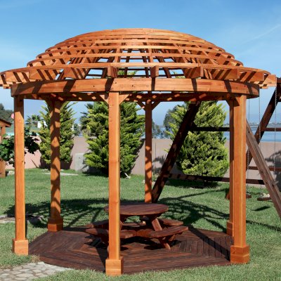 Wooden Dome Pergola (Options: 16' Diameter, with Deck in Coffee Stain, Douglas-fir, Open Roof with Slats at 6", 9' Posts, No Electrical Wiring Trim, 6-Post Anchor Kit for Concrete, Transparent Premium Sealant). Photo Also shows a Round Picnic Table and a Rory's Swing Set in Background.