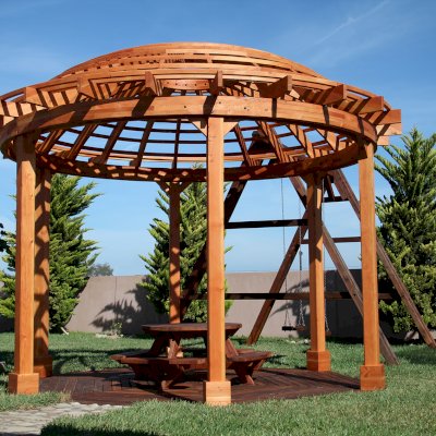 Wooden Dome Pergola (Options: 16' Diameter, with Deck in Coffee Stain, Douglas-fir, Open Roof with Slats at 6", 9' Posts, No Electrical Wiring Trim, 6-Post Anchor Kit for Concrete, Transparent Premium Sealant). Photo Also shows a Round Picnic Table and a Rory's Swing Set in Background.