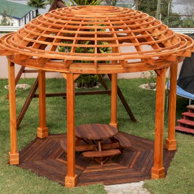 Wooden Dome Pergola (Options: 16' Diameter, with Deck in Coffee Stain, Douglas-fir, Open Roof with Slats at 6", 9' Posts, No Electrical Wiring Trim, 6-Post Anchor Kit for Concrete, Transparent Premium Sealant). Photo Also shows a Round Picnic Table and a Rory's Swing Set in Background.