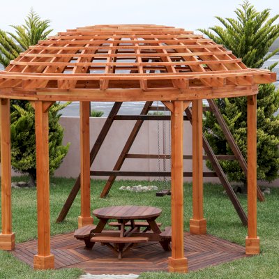 Wooden Dome Pergola (Options: 16' Diameter, with Deck in Coffee Stain, Douglas-fir, Open Roof with Slats at 6", 9' Posts, No Electrical Wiring Trim, 6-Post Anchor Kit for Concrete, Transparent Premium Sealant). Photo Also shows a Round Picnic Table and a Rory's Swing Set in Background.