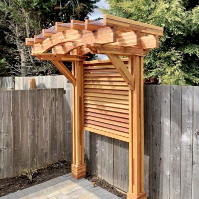 Two-Post Arched Wood Arbor (Options: 6' x 3', Mosaic Redwood, 7' Posts Height, 2-Post anchor Kit for High-Wind, Custom Louvered Half Height Privacy Wall Added by Customer Request, Vertical Post Decorative Trims, with Rain Guard, Transparent Premium Sealant). Photo Courtesy of E. Baechler of Portland, Oregon.