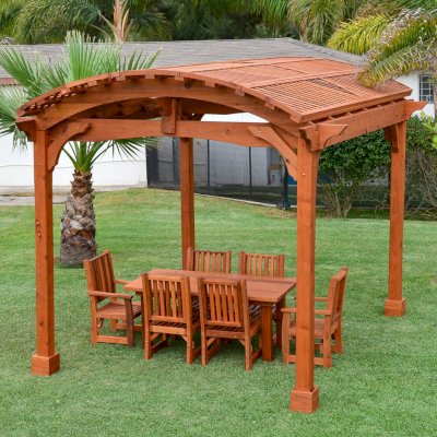 Viking Pergola DIY Kits (Options: 12' L x 14' W, Mature Redwood, No Electrical Wiring Trim Kit, No Curtain Rods, Transparent Premium Sealant). Photo Also Shows a Patio Table Set with Ruth Chairs Under the Pergola. 