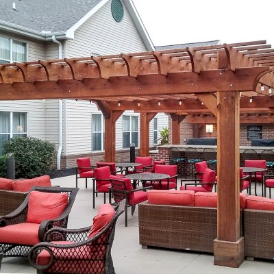 Traditional Wooden Garden Pergola (Options: 20' x 20' [2 Smaller Pergolas Shown in the Background], California Redwood, Electrical Wiring Trim for 1 Post, Open Roof with Slats at 12" and Rafters at 18", 4-Post Anchor Kit for Concrete, No Ceiling Fan Bases, No Privacy Panels, No Curtain Rods, Transparent Premium Sealant). Thicker Lumber by Custom Request, 2 x 12 Rafters & Supports, 10 x10 Posts. Photo Courtesy of Homewood Suites by Hilton, Mechanicsburg, PA.